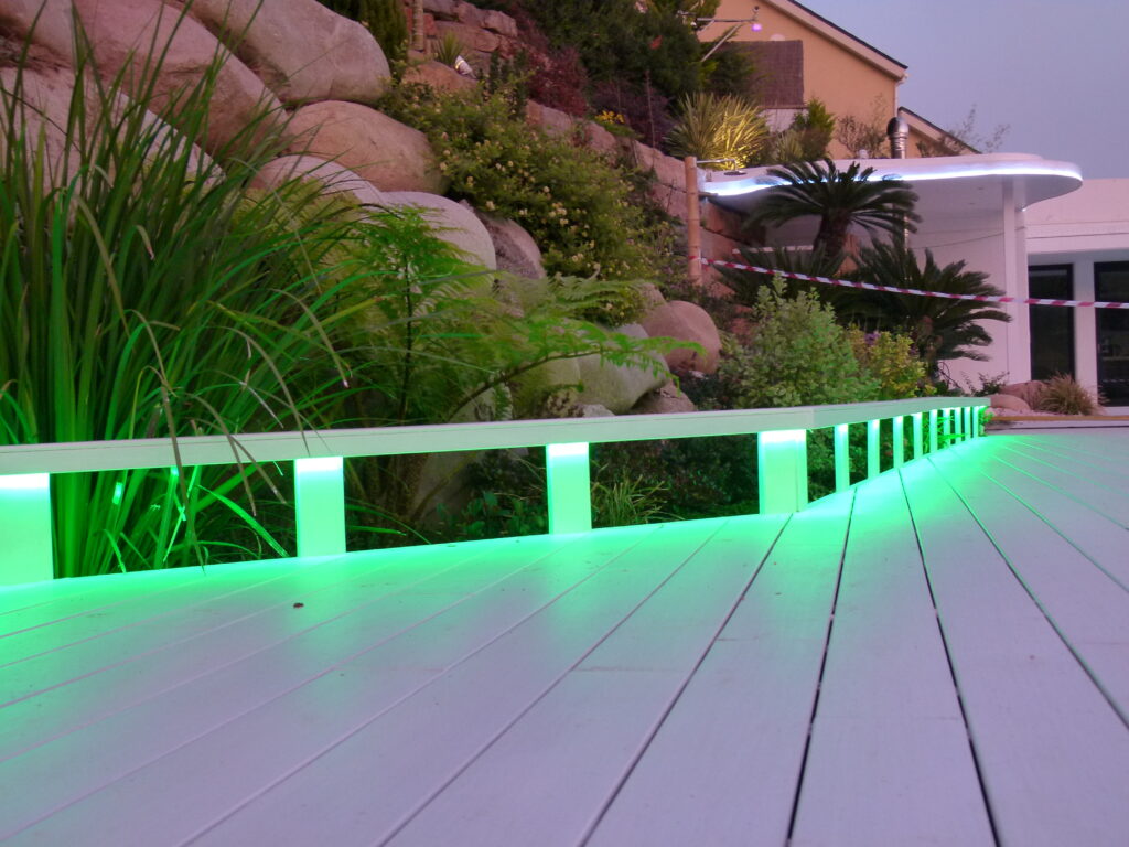 Camino blanco de madera con iluminación de exterior verde